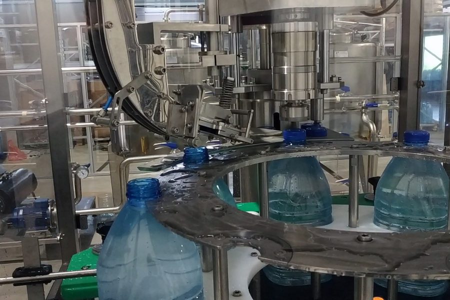 Bottled water production line, an automatic machine fills large bottles with still water.
