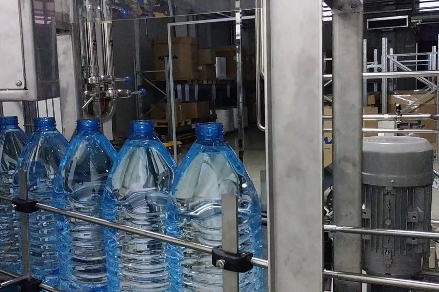 Automatic line filling bottles with water, the bottles move on to capping.